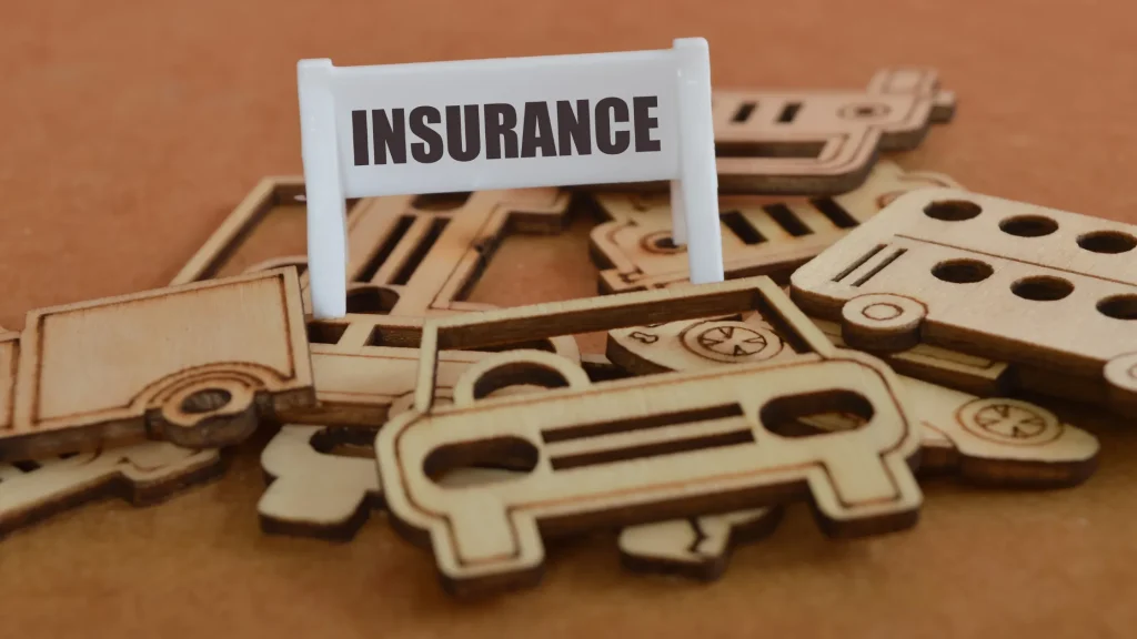 Wooden car icons scattered around a sign that says 'INSURANCE', linking to the concept of Digital Marketing Agency Insurance.